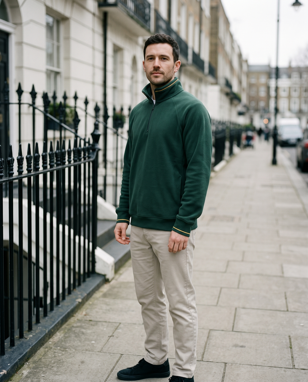 Man wearing forest green half-zip fleece beside iron railings
