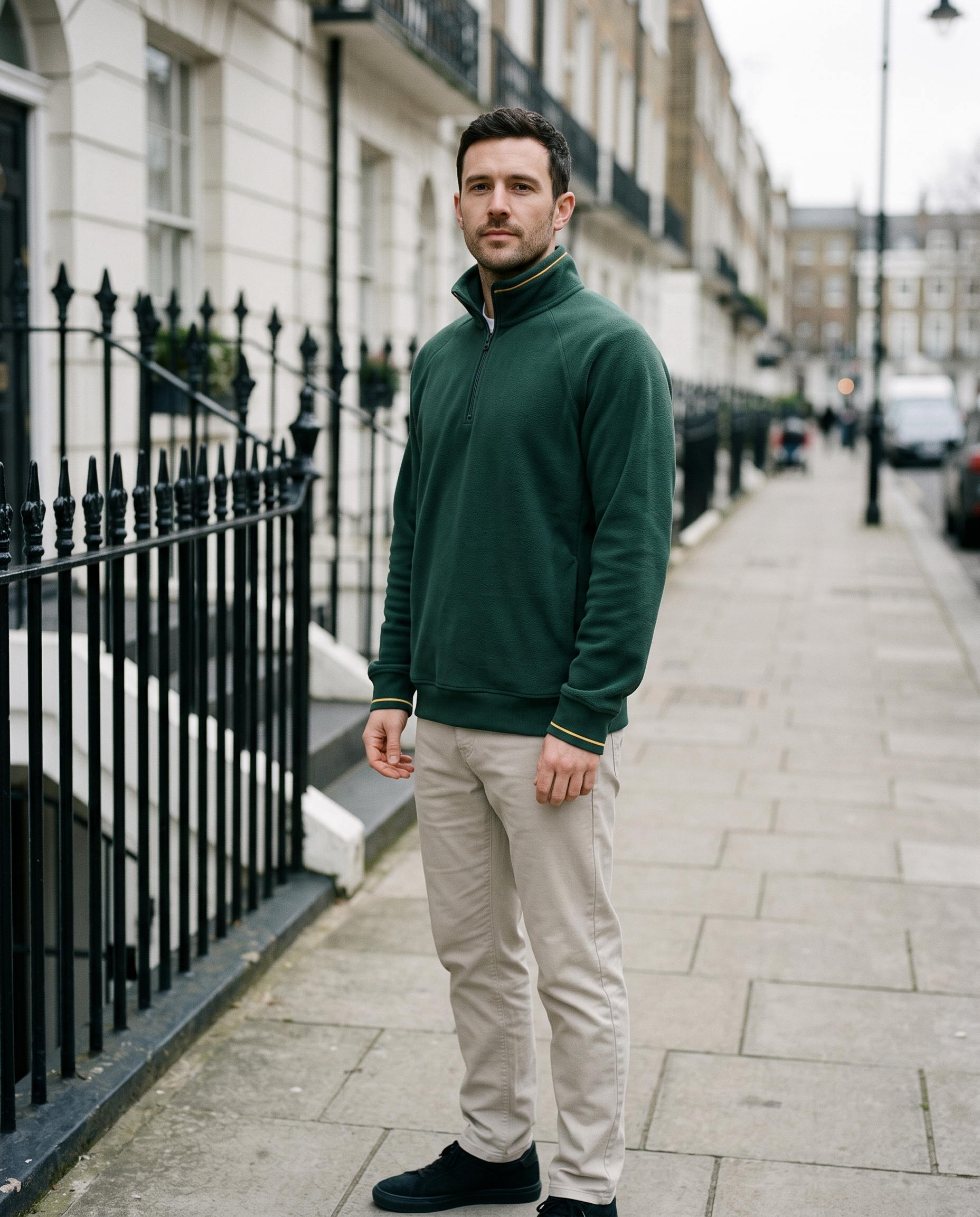 Man wearing forest green half-zip fleece beside iron railings