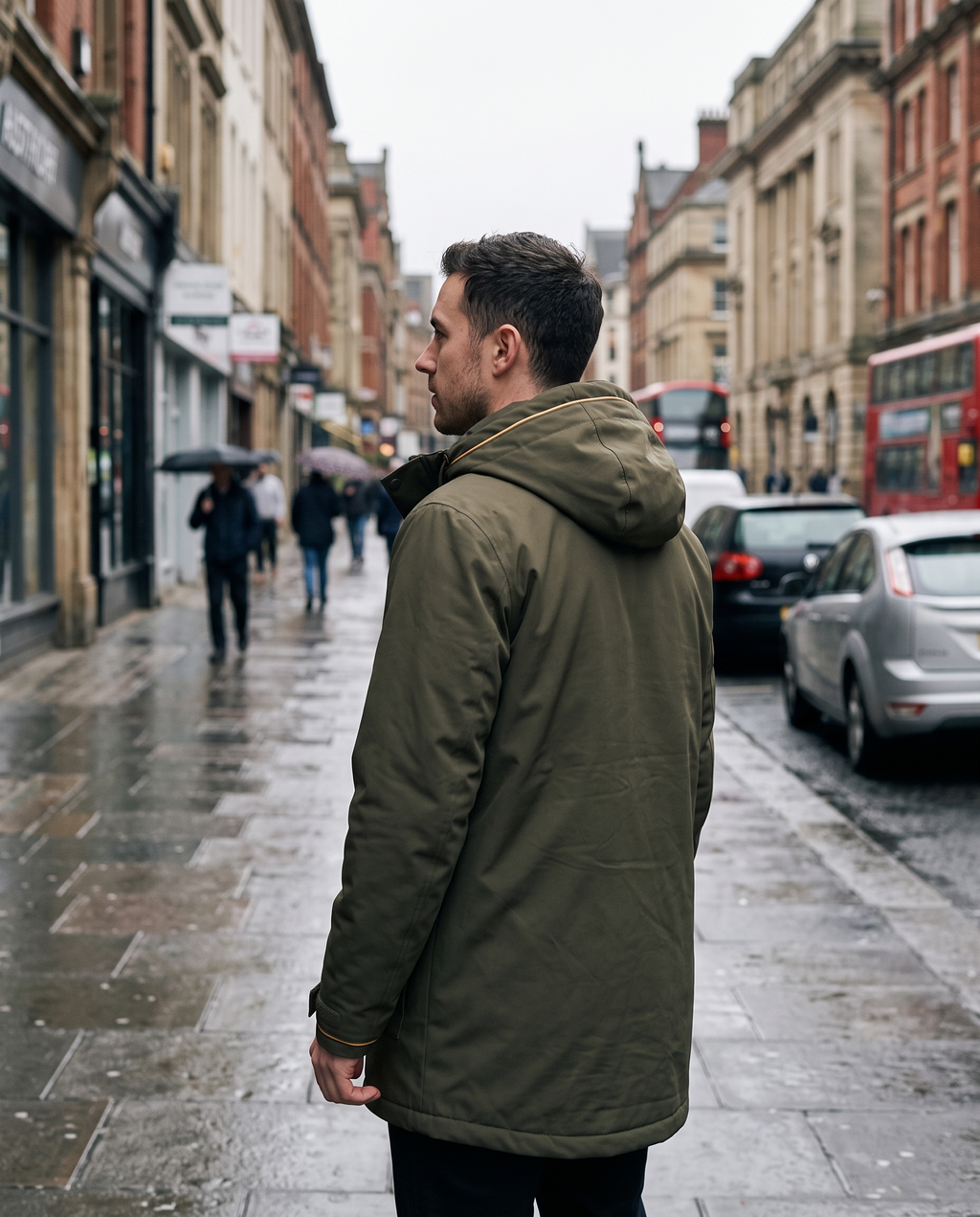 Man in olive green parka with hood up, seen from behind